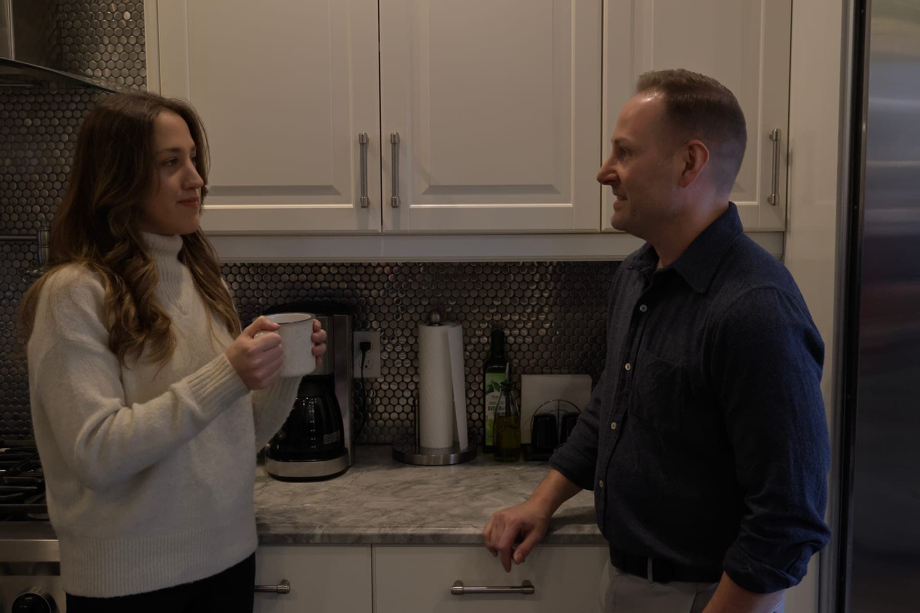 Thomas West speaking with a woman in a kitchen